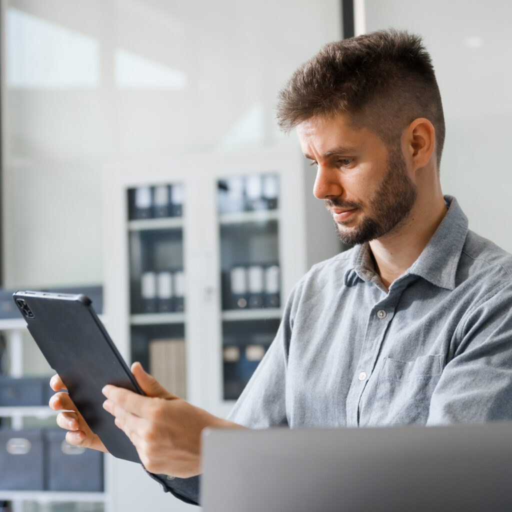 Business professional reviewing financial management software on a digital tablet in a modern office setting.