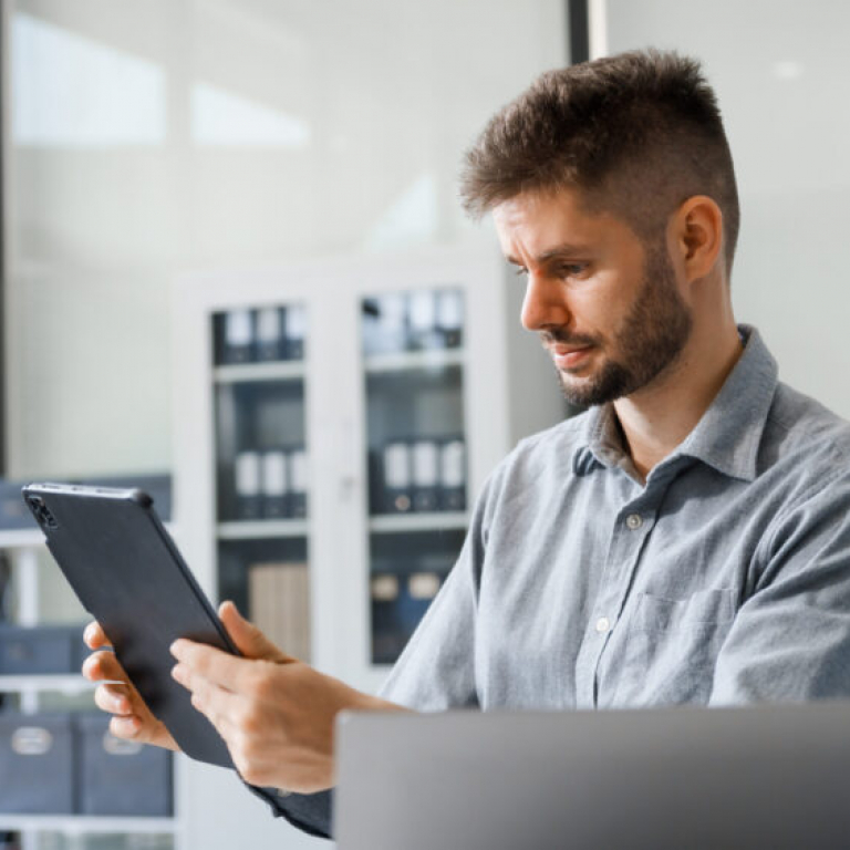 Business professional reviewing financial management software on a digital tablet in a modern office setting.