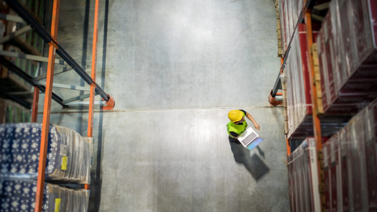 Warehouse worker using a laptop to manage inventory and processes, representing Sage 200 implementation for distribution and operations management.
