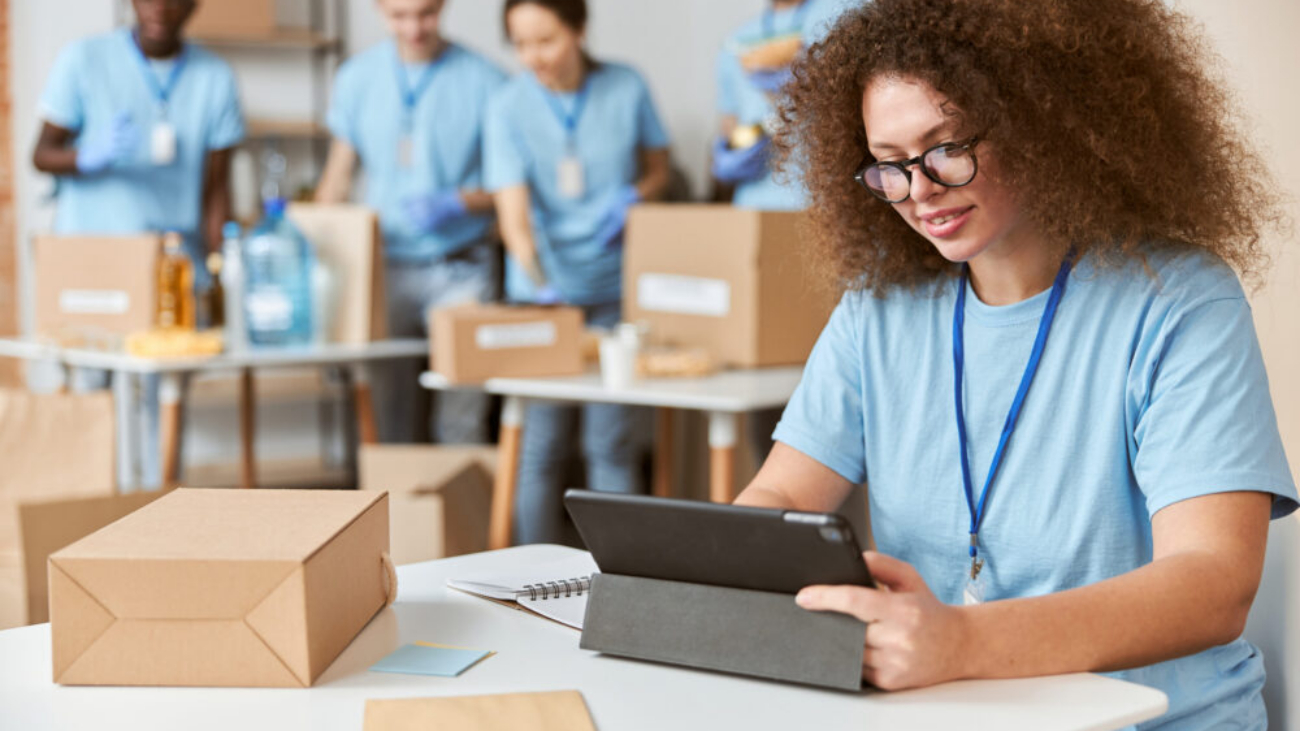 Young woman volunteer in blue uniform holding a laptop for UK charity finance management