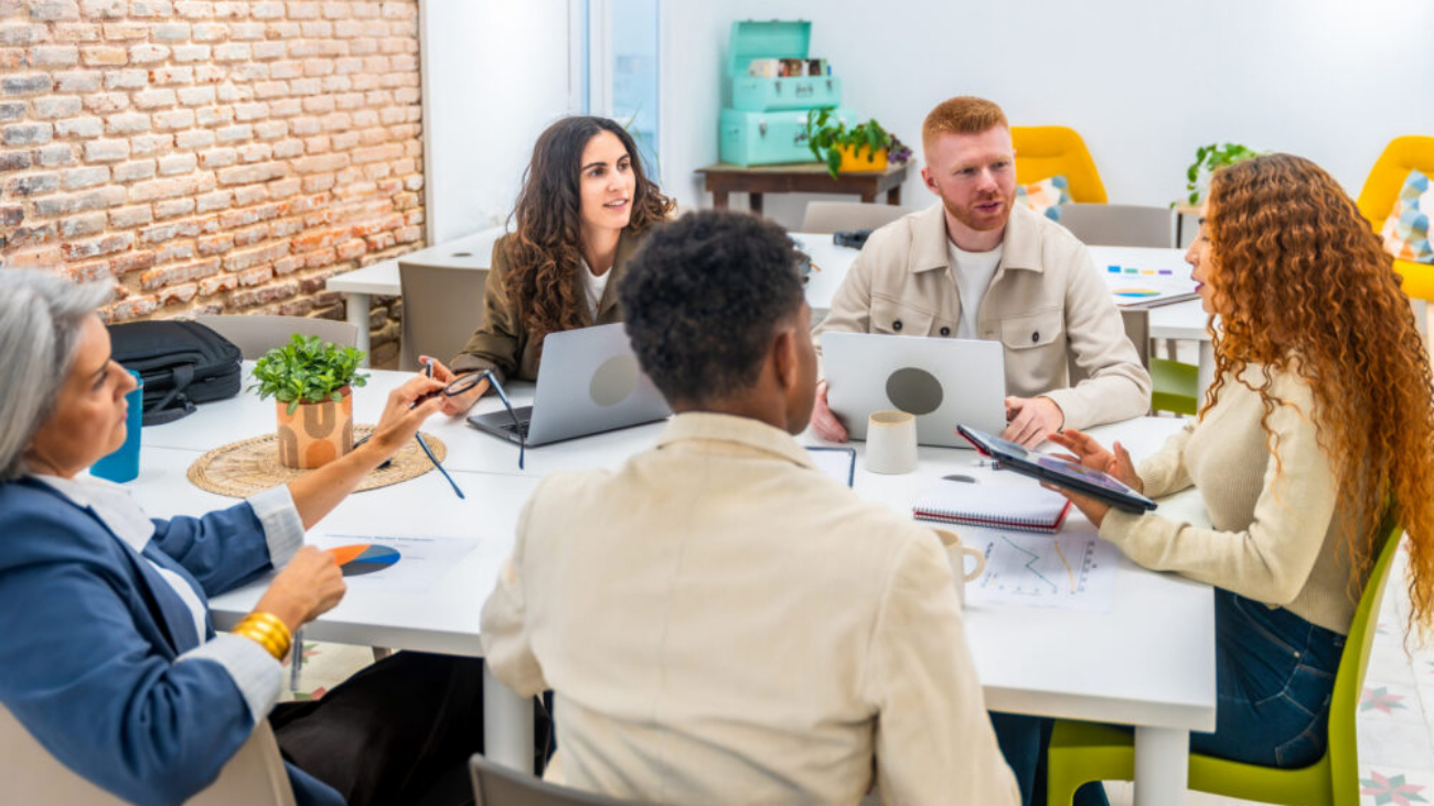 Diverse non-profit team collaborating in office using charity accounting software and Sage Cloud dashboards