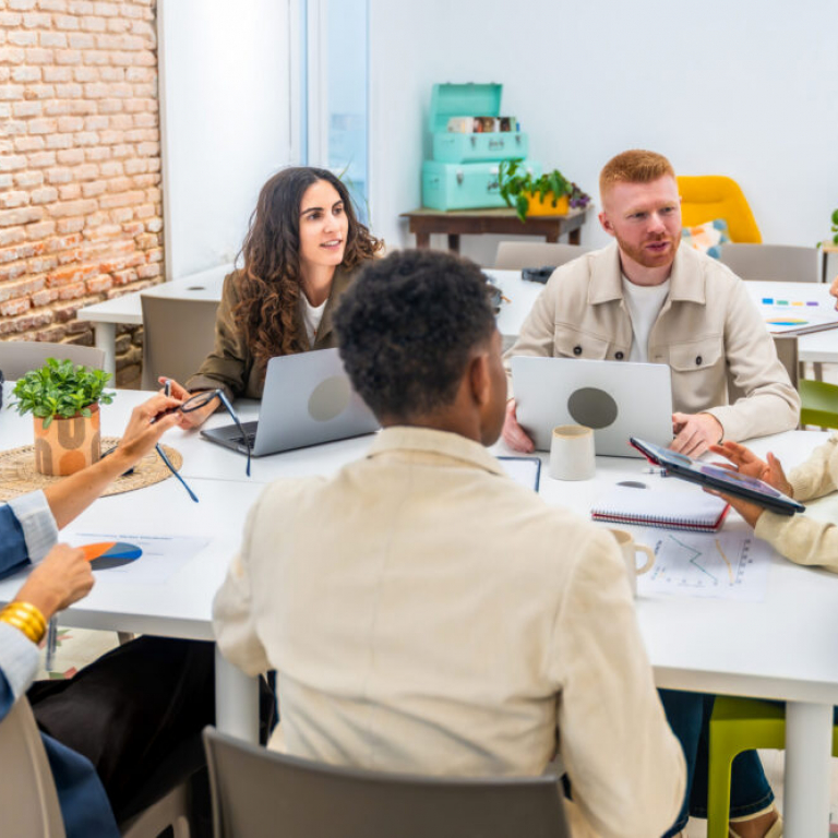Diverse non-profit team collaborating in office using charity accounting software and Sage Cloud dashboards