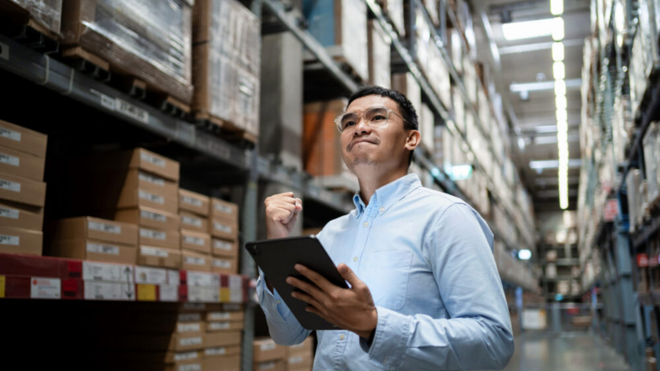 Warehouse manager using Sage 200 accounting software on a tablet to manage inventory, reporting and business operations.