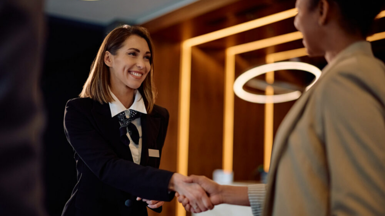 Female hotel concierge shaking hands with a businesswoman, representing accounting software for hospitality industry businesses.