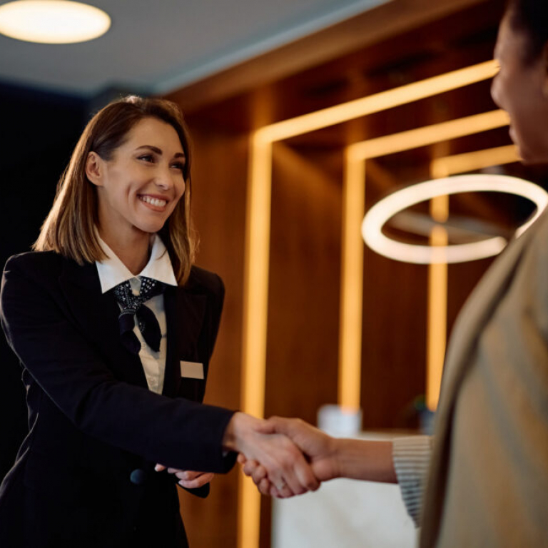 Female hotel concierge shaking hands with a businesswoman, representing accounting software for hospitality industry businesses.