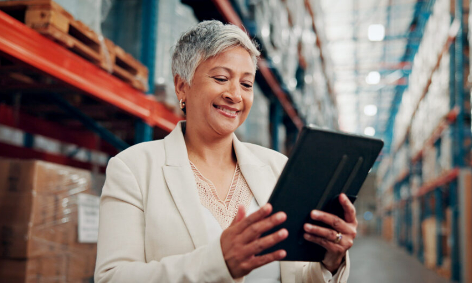 Warehouse employee using a tablet to access AI-powered financial management software for real-time business insights.