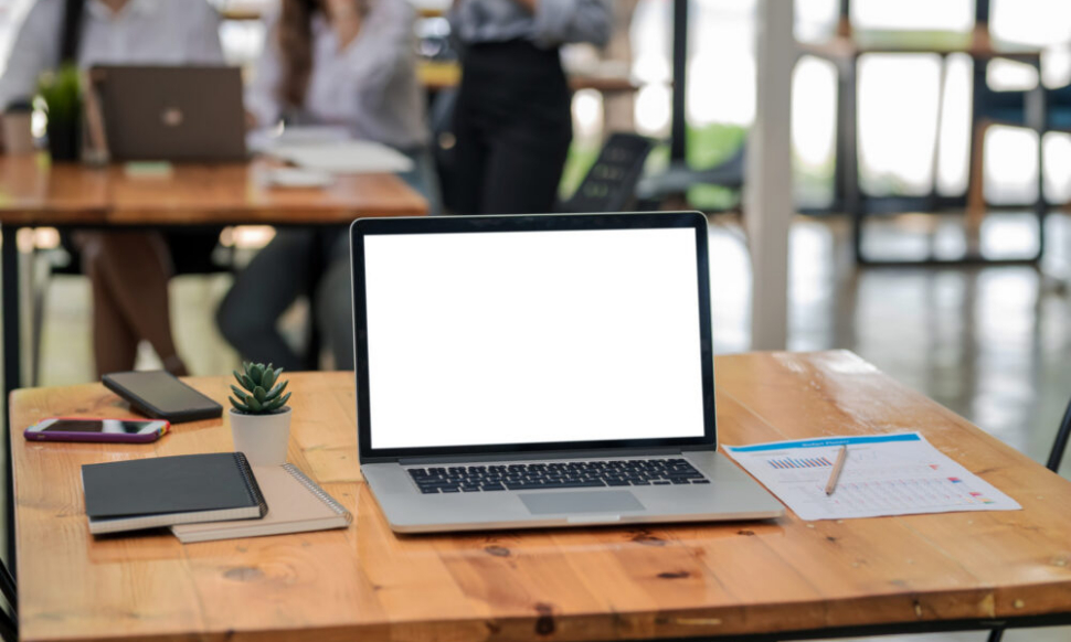 Laptop with blank screen on wooden desk representing Sage Intacct and Sage 200 ERP comparison for UK businesses